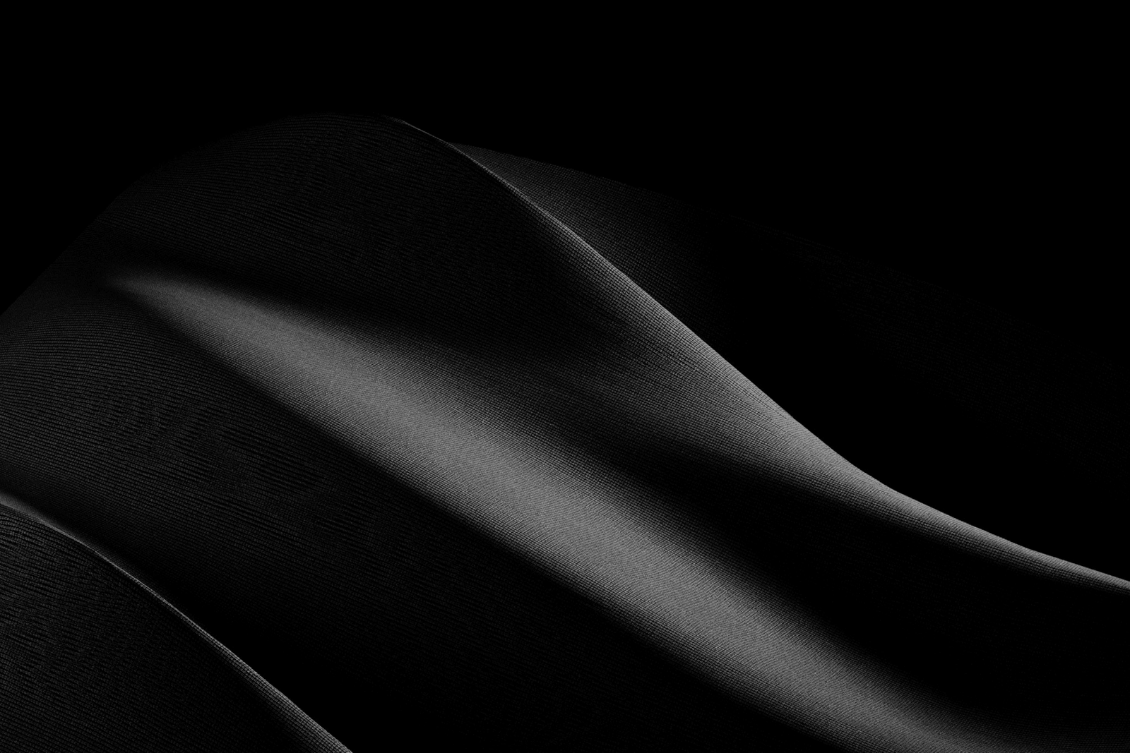 Abstract dark woven textile with diagonal folds and soft shadows